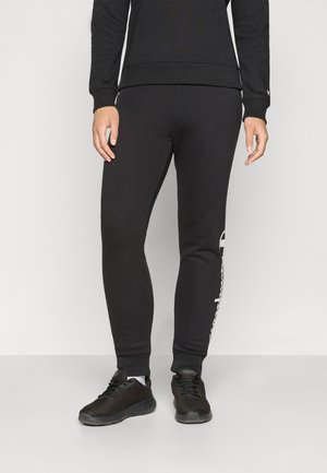 Svart bomullssvetter har en slim fit med ribbede mansjetter, logo-detalj på siden, og er kombinert med svarte joggesko.