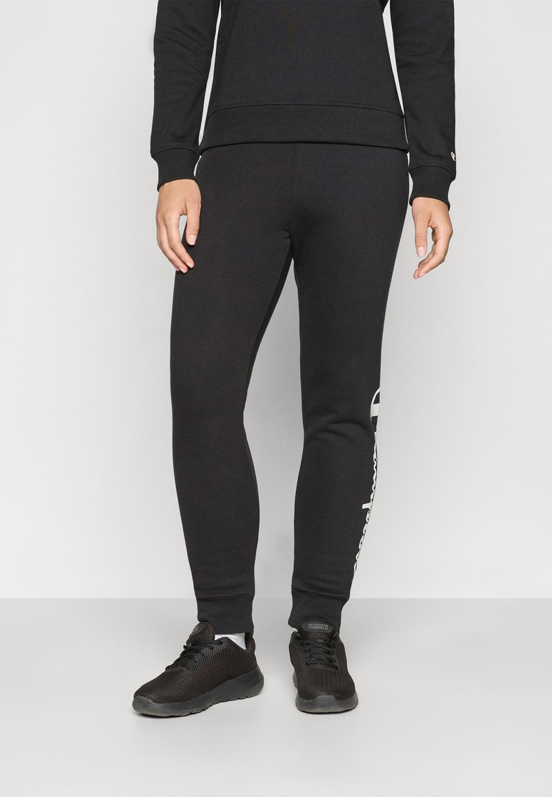 Svart bomullssvetter har en slim fit med ribbede mansjetter, logo-detalj på siden, og er kombinert med svarte joggesko.