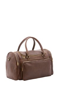 Bruine leren sporttas met gouden accenten, twee handgrepen en meerdere ritssluitingen. Gevarieerde textuur met een gestructureerde vorm.