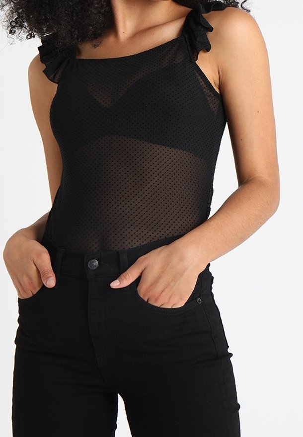 Body noir transparent avec motif à pois, bretelles à volants. Associé à un jean noir taille haute avec poches avant.