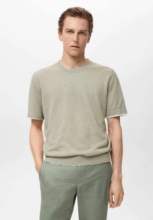 Hellgrüner kurzärmeliger Pullover mit Rundhalsausschnitt, gerippten Bündchen und weicher Textur, kombiniert mit passenden Hosen.