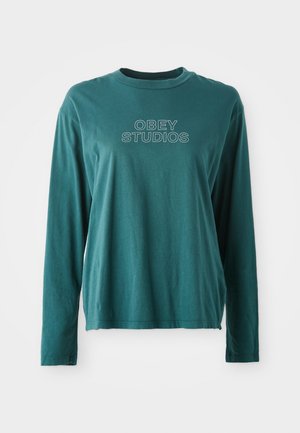 Camisola de manga longa em verde-água, feita de algodão suave. Apresenta um decote redondo e um gráfico em branco "OBEY STUDIOS" na frente. Design simples.