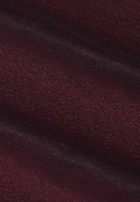 Tissu bordeaux avec une surface fine et texturée, présentant un léger éclat et un tombé doux. Le tissage offre une sensation lisse mais légèrement en relief.