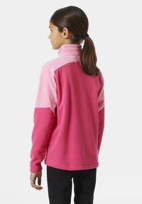 Polarowy pulower w odcieniach różu, z wysokim kołnierzem, długimi rękawami i luźnym krojem. Miękka tekstura z motywem w blokach kolorystycznych.