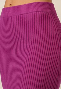Ribbed lila Rock mit hohem Taillenbund und dehnbarem Material, seitlich präsentiert, um seine enge Passform und das Design hervorzuheben.
