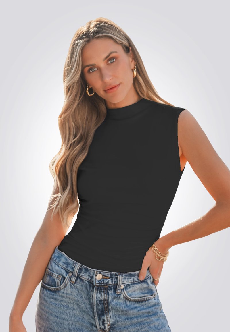 Top nero senza maniche con collo alto, design aderente, realizzato in un materiale liscio, abbinato a jeans azzurri a vita alta.
