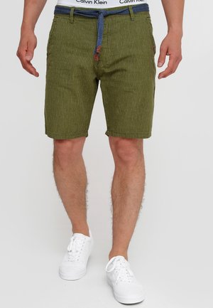 Grün gestreifte Shorts mit blauer Kordel und Taschen, aus strukturiertem Stoff. Getragen mit weißen Sneakers und sichtbarem Calvin Klein Bündchen.