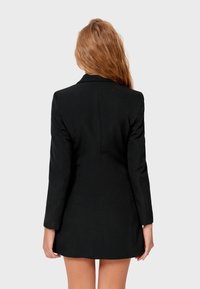 Black blazer with long sleeves and a fitted design. Features a classic lapel collar and a smooth fabric texture. Back view shows tailoring details.