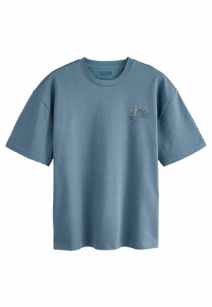T-shirt bleu à manches courtes avec petite broderie florale et texte "Flower Market Amsterdam" sur la poitrine gauche.