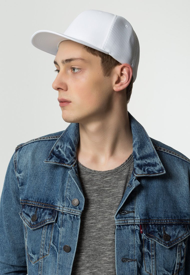 White cap with mesh back, curved brim, worn with a denim jacket and gray striped t-shirt. Close-up profile view showcasing the cap’s design.