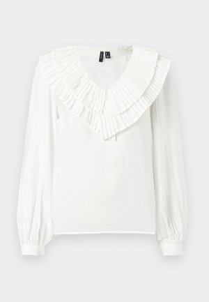 Blouse blanche avec un décolleté en V et un col volanté en couches. Manches longues avec poignets élastiques, fabriquée dans un tissu léger et texturé.
