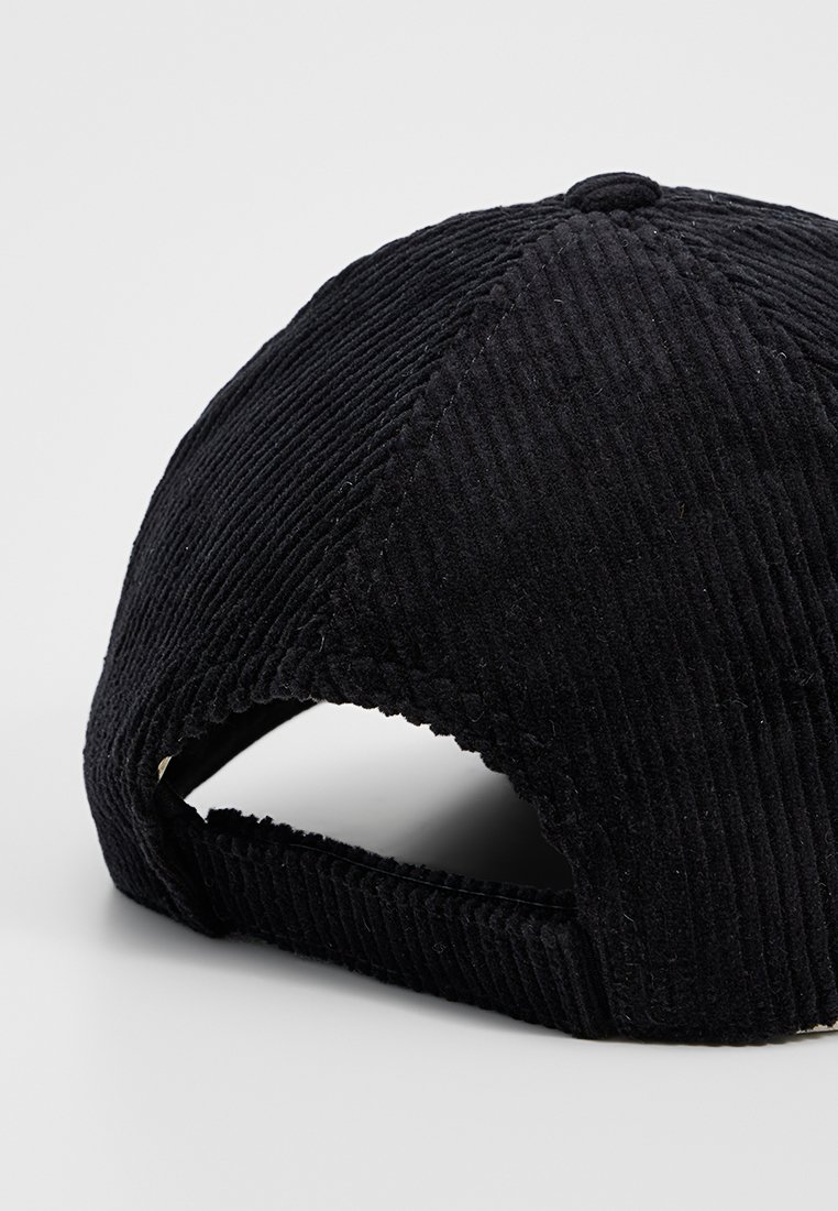 Gorra de béisbol de corduroy negro con visera curva, superficie texturizada y una correa ajustable en la parte posterior.