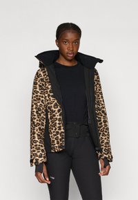 Luipaardprint gewatteerde jas met een zwarte binnenvoering, gekenmerkt door een hoge kraag en elastische manchetten. Draag het over een zwarte top en broek.