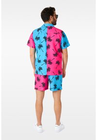 Kortærmet skjorte med knapper og shorts i et delt design; den ene side er turkis, den anden side er varm pink med sorte palme mønstre.