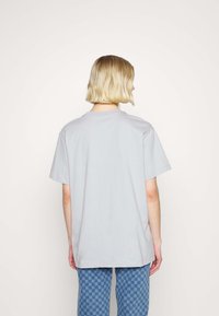 Ljusgrå överdimensionerad t-shirt med rund halsringning, korta ärmar och en mjuk tygtextur, kombinerad med blå rutiga byxor.