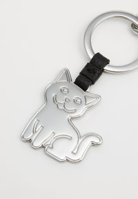 Silver metal cat-shaped keychain with a black leather strap, featuring smooth lines and a playful facial design.