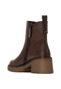 Stivaletti in pelle marrone con zip laterale, tacco beige spesso e linguetta sul retro. Presentano una texture liscia con dettagli di cucitura sottili.