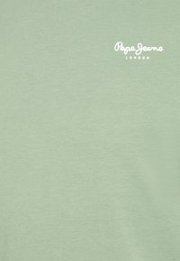 Světlé zelené bavlněné tričko s hladkou texturou a malým bílým logem s nápisem „Pepe Jeans London“. Bez dalších vzorů nebo ozdob.