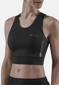 Bra sportivo nero realizzato in materiale liscio e elastico. Presenta un ampio scollo, design con schiena a corsetto e un piccolo logo sul lato sinistro.