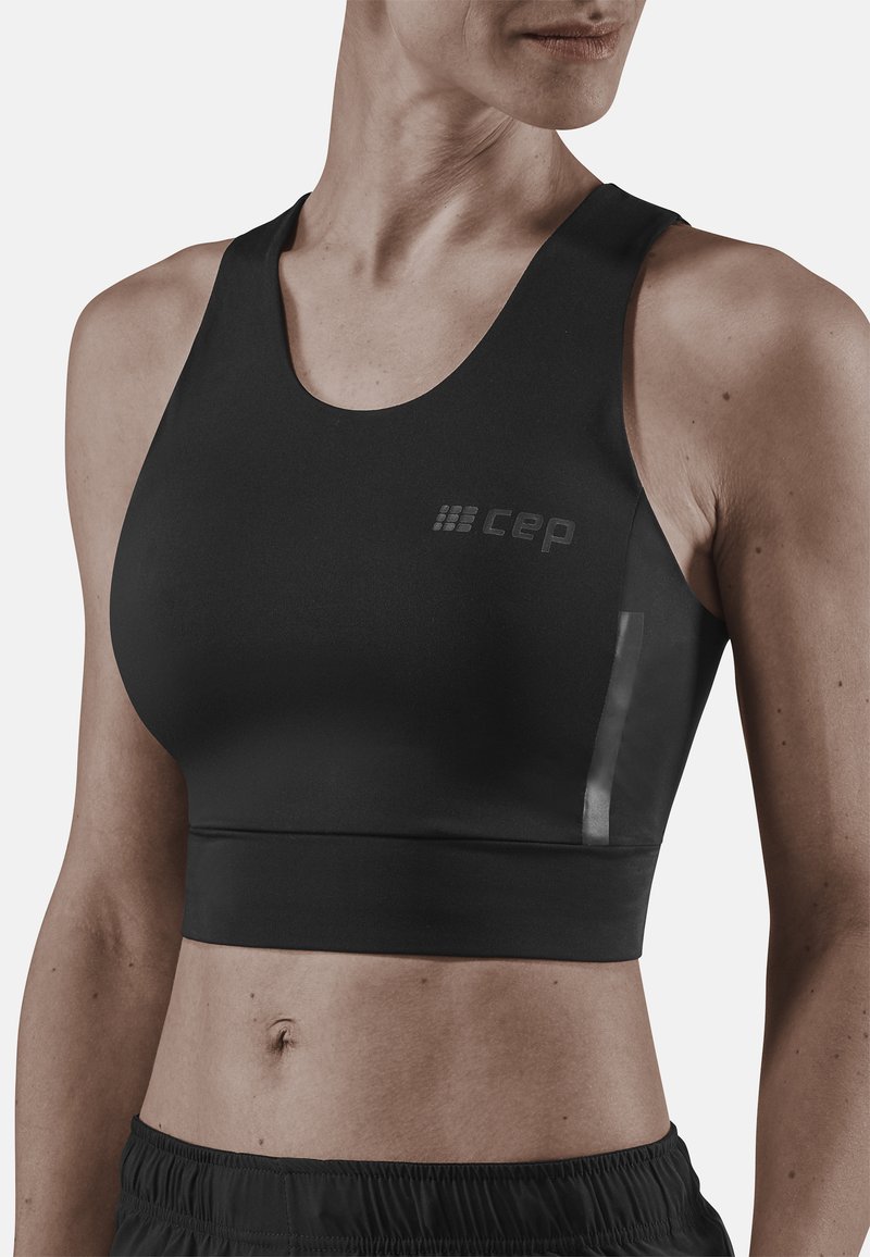 Bra sportivo nero realizzato in materiale liscio e elastico. Presenta un ampio scollo, design con schiena a corsetto e un piccolo logo sul lato sinistro.