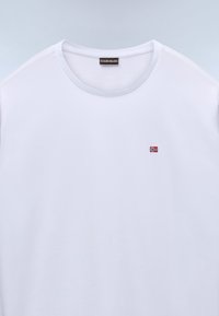 Hvid bomulds T-shirt med rund hals og korte ærmer. Har et lille broderet norsk flag på venstre bryst. Glat tekstur.