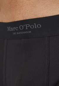 Sous-vêtements noirs côtel�és de Marc O'Polo présentant une ceinture élastique douce avec un texte logo imprimé. Le tissu est lisse avec une texture subtile.