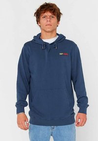 Navy blue hoodie made of cotton. Features a kangaroo pocket, ribbed cuffs, and drawstring hood. Displays "RIP CURL" logo in red and yellow.