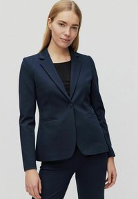 Marinblazern har en skräddarsydd design, gjord av ett slätt tyg, med notched lapel, enknappsstängning och framfickor.