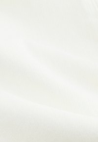 Gros plan sur un tissu blanc lisse avec une texture subtile en diagonale et de doux plis.