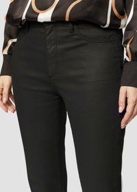 Schwarze Hosen aus einem glatten, dehnbaren Stoff. Sie verfügen über ein tailliertes Design mit dezenten Steppnähten und klassischer Fünf-Taschen-Optik.