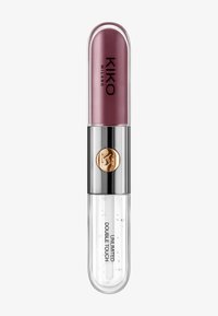 Läppprodukt med ett rundat, transparent rör. Översta delen innehåller en metallisk, skimrande mauve nyans; botten har en klar glans med bubblor.