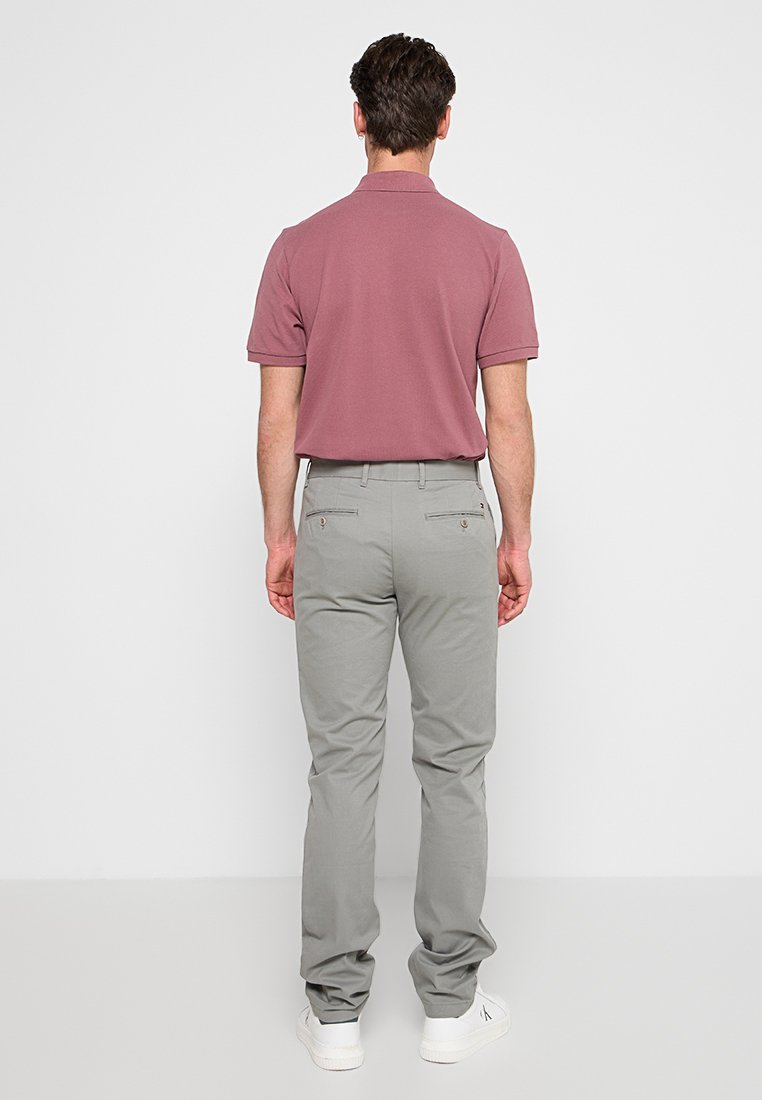 Kurzärmliges, hellrosa Polohemd, kombiniert mit hellgrauen Hosen; hat eine schlanke Passform mit zwei Gesäßtaschen und weißen Sneakern.
