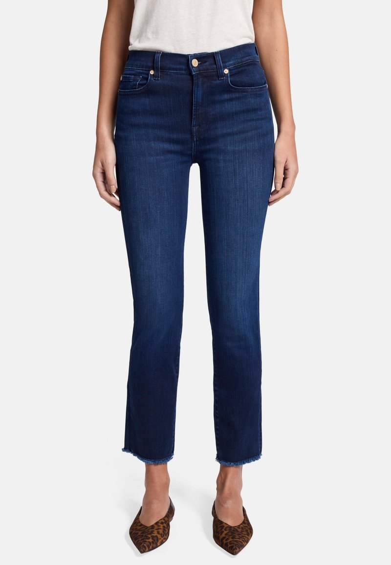 Granatowe, skrócone dżinsy z wysokim stanem, lekko elastyczne, z postrzępionym dołem, w połączeniu z brązowym obuwiem na obcasie w lamparcie cętki.