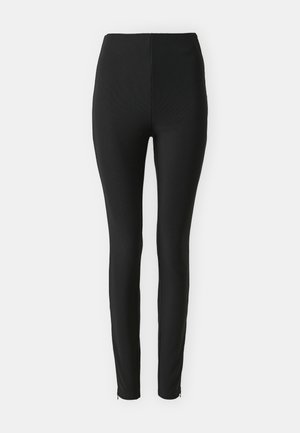 Leggings negre cu talie înaltă, cu o textură ribbed. Design ajustat, picioare conice, cu accente cu fermoar la tivurile gleznelor. Material neted.