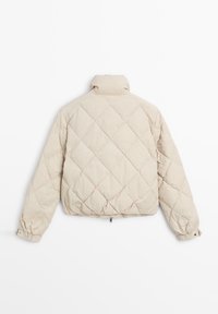 Beżowa pikowana kurtka o krótkim kroju, z wysokim kołnierzem, elastycznymi mankietami i widocznym suwakiem u dołu. Całość ozdobiona wzorem w romby.