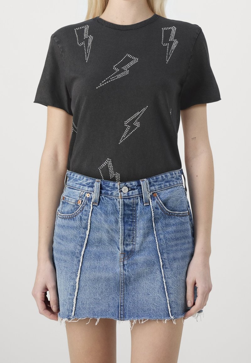 Zwarte t-shirt met zilveren bliksemflitspatronen, gecombineerd met een lichtblauwe denim rok met rafelige zoom, featuring een hoge taille en voorzakken.