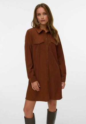 Robe chemise marron avec un devant à boutons, deux poches poitrine, des manches longues et une texture douce ; associée à des bottes grises montantes.