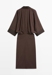 Donkerbruine midi-jurk met lange mouwen, brede manchetten, getailleerde taille en een split aan de achterkant, gezien van achteren op een witte achtergrond.