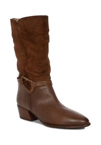 Bota marrón hasta la rodilla hecha de ante y cuero texturizado; cuenta con una correa decorativa trenzada y un tacón bajo. Diseño de puntera afilada.