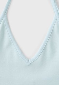 Gros plan sur un tissu bleu clair avec un décolleté en V profond et des coutures visibles le long des bords.