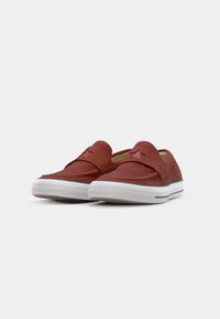 Sapatos slip-on vermelhos com um acabamento de camurça texturizada, apresentando um destaque de estrela e uma sola de borracha branca com aderência texturizada.