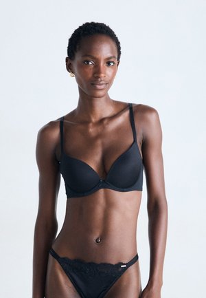 Zwart lingeriesetje met een gepadded bh met verstelbare bandjes en een met kant afgewerkte string. Soepele stof met een subtiele glans en een minimalistisch ontwerp.