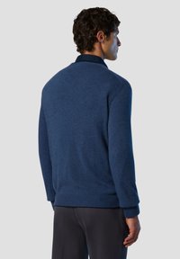 Marineblaues Strickoberteil mit Rundhalsausschnitt und gerippten Bündchen. Glatte Textur, leicht taillierte Silhouette und minimalistisches Design.