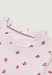 Lichtroze geribde T-shirt met een ronde halslijn, voorzien van verspreide rode lieveheersbeestjespatronen. Zachte stof met een normale pasvorm.