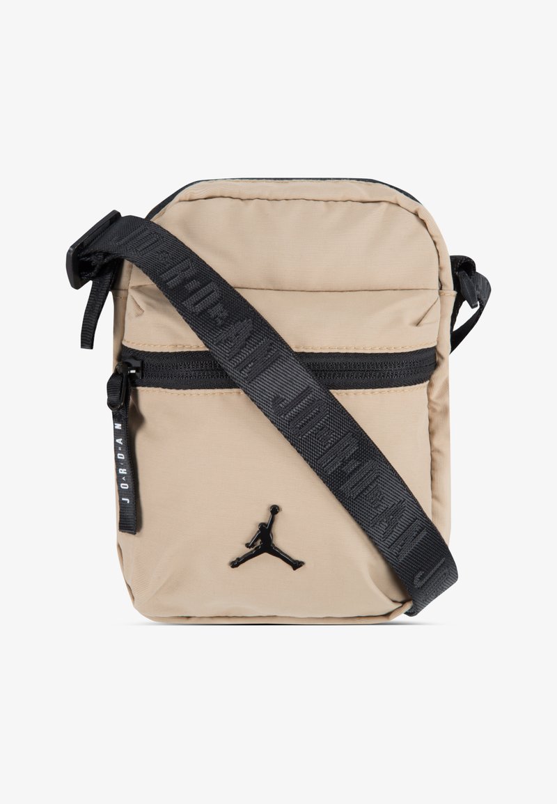 Beige nylon schoudertas met een zwarte ritszak, verstelbare schouderband met de tekst "JORDAN", en een zwart reliëflogo aan de voorkant.