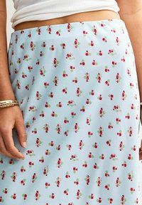 Floral midi skirt in light blue fabric featuring scattered red flower patterns and green accents. Smooth texture and flowy design.