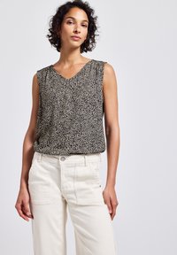 Top sin mangas en estampado de leopardo negro y beige, con escote en V y textura suave; combinado con pantalones de pierna ancha en color marfil que cuentan con bolsillos frontales.