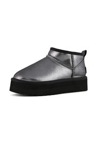 Botines metálicos plateados con punta redondeada, suela gruesa negra y costura decorativa a lo largo del costado. Textura lisa y diseño minimalista.