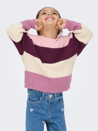 Pull en tricot à larges rayures horizontales crème, rose clair, rose foncé et violet. Associé à un jean bleu avec des accents en forme de cœur rose.