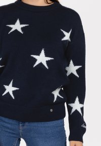 Marineblauer Strickpullover mit weißen Sternmustern, einem runden Halsausschnitt und einem gerippten Saum. Enthält ein kleines Logodetail am unteren Ende.